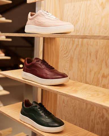 Sneakers i rosa, burgunder og grønt skinn på trehyller
