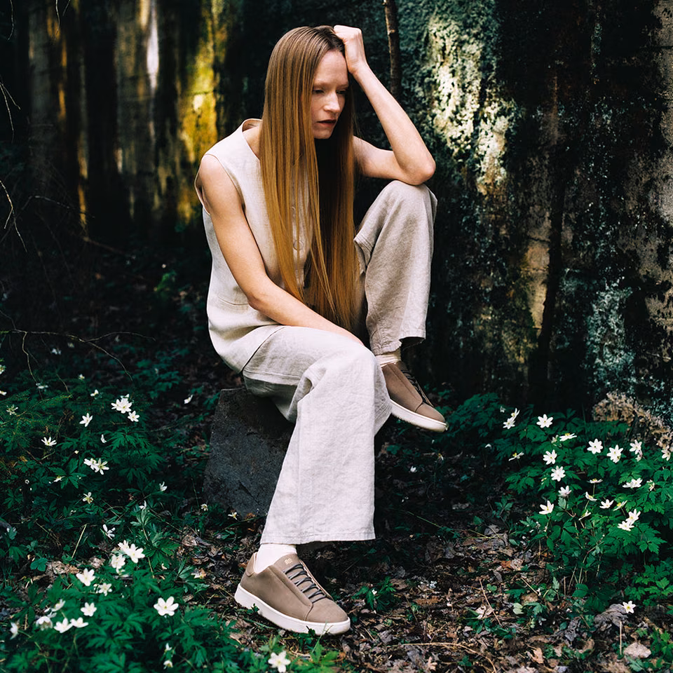 Modell med Zen-sneakers i sandfarget nubuck i skogen